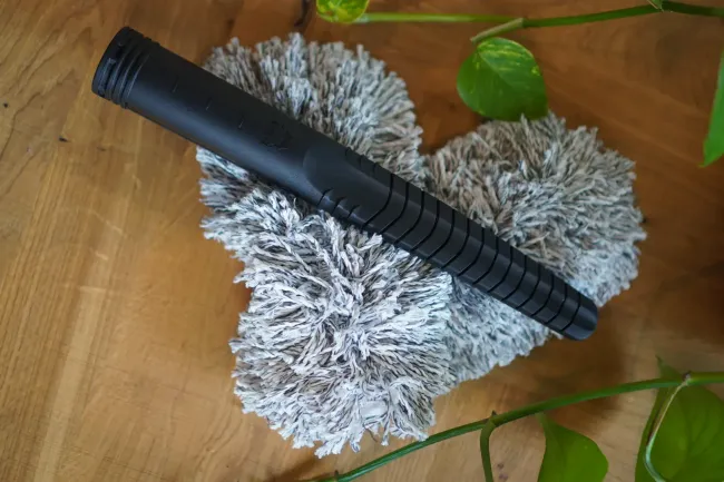 A black brush is sitting on top of a gray brush on a wooden table.