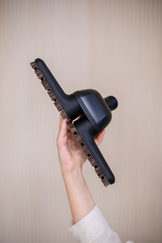 A person is holding a vacuum cleaner brush in their hand.