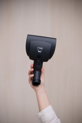 A person is holding a black vacuum cleaner head in their hand.