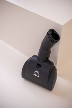 A black vacuum cleaner brush is sitting on a white surface.
