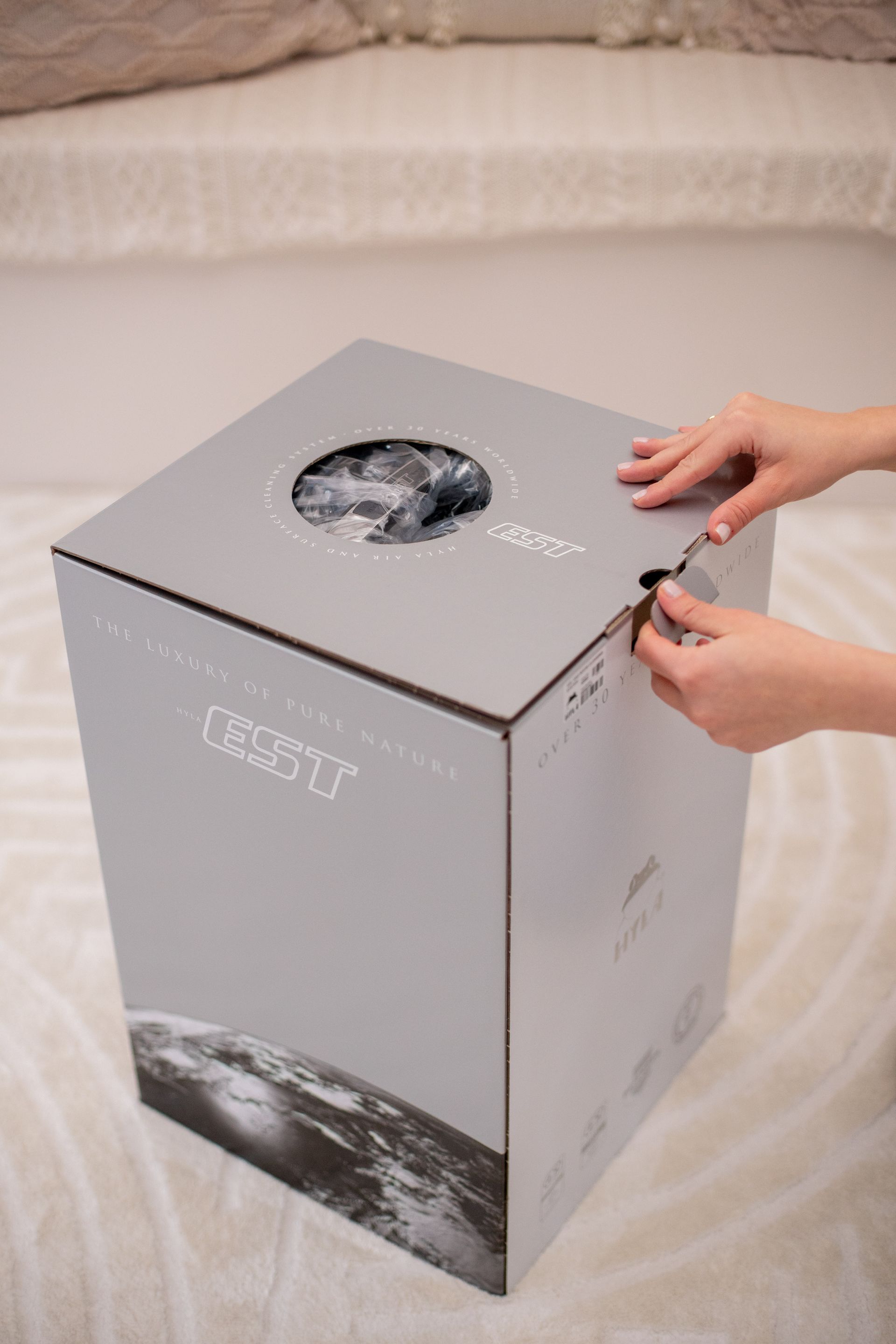 A person is opening a cardboard box with a picture of the earth on it.