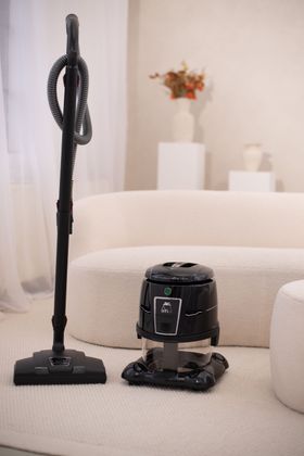 A vacuum cleaner is sitting next to a couch in a living room.