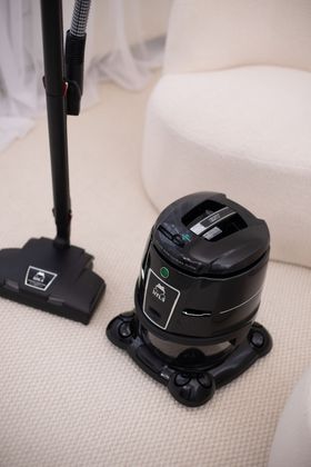 A vacuum cleaner is sitting on a couch next to a chair.