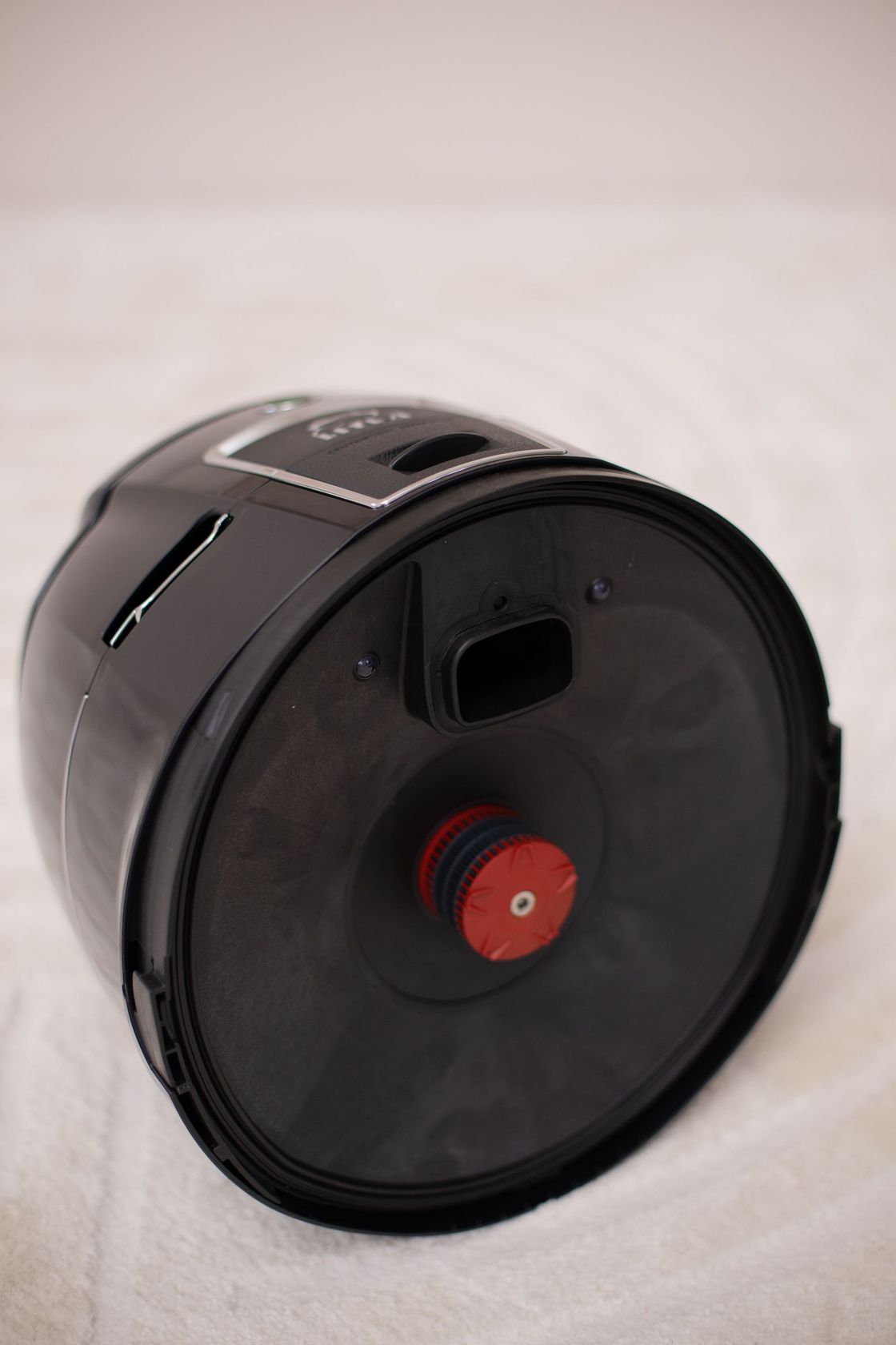 A black vacuum cleaner with a red button on the bottom