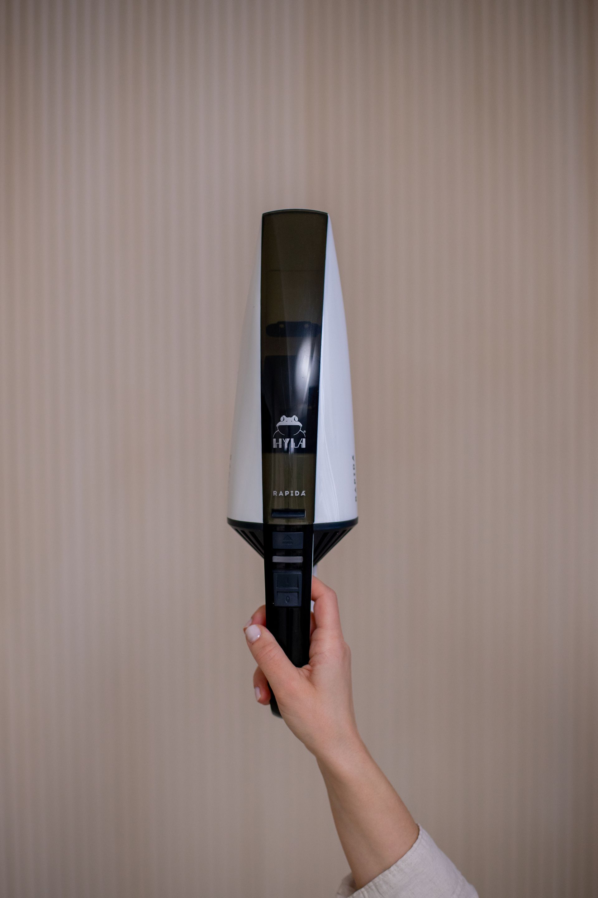 A person is holding a vacuum cleaner in their hand.