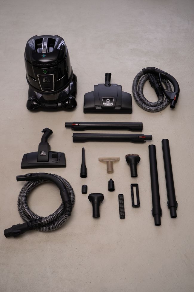A black vacuum cleaner is surrounded by various attachments
