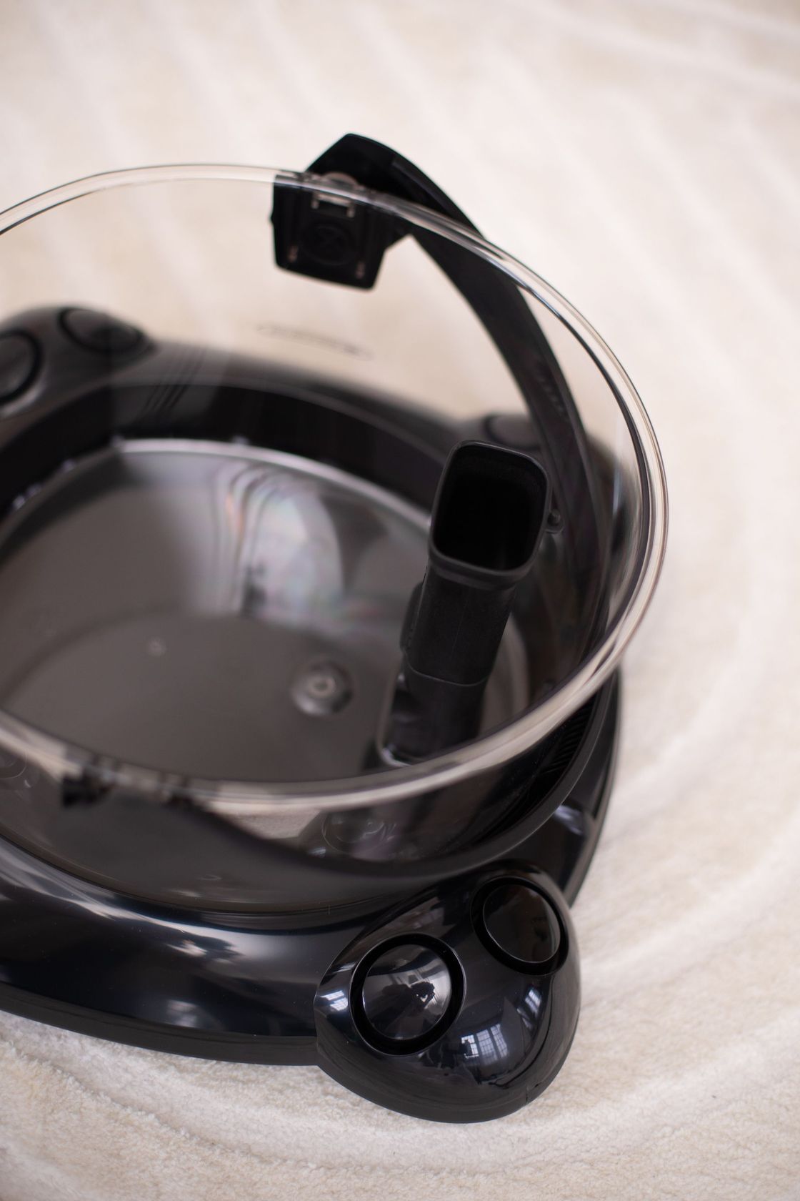 A black pot with a clear lid is sitting on a white surface.