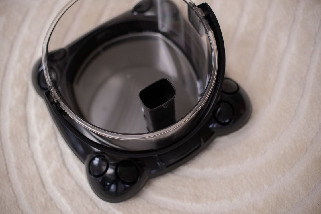A black vacuum cleaner is sitting on a white carpet.