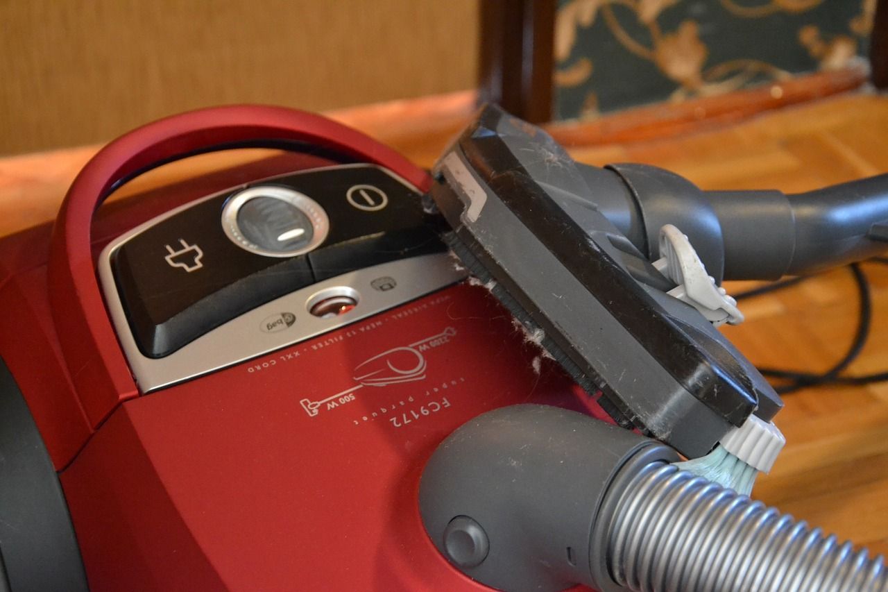 A red vacuum cleaner is sitting on a wooden floor