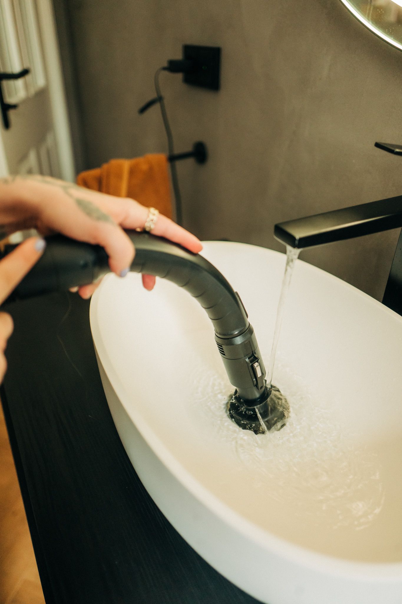 A person is cleaning a sink with a vacuum cleaner.