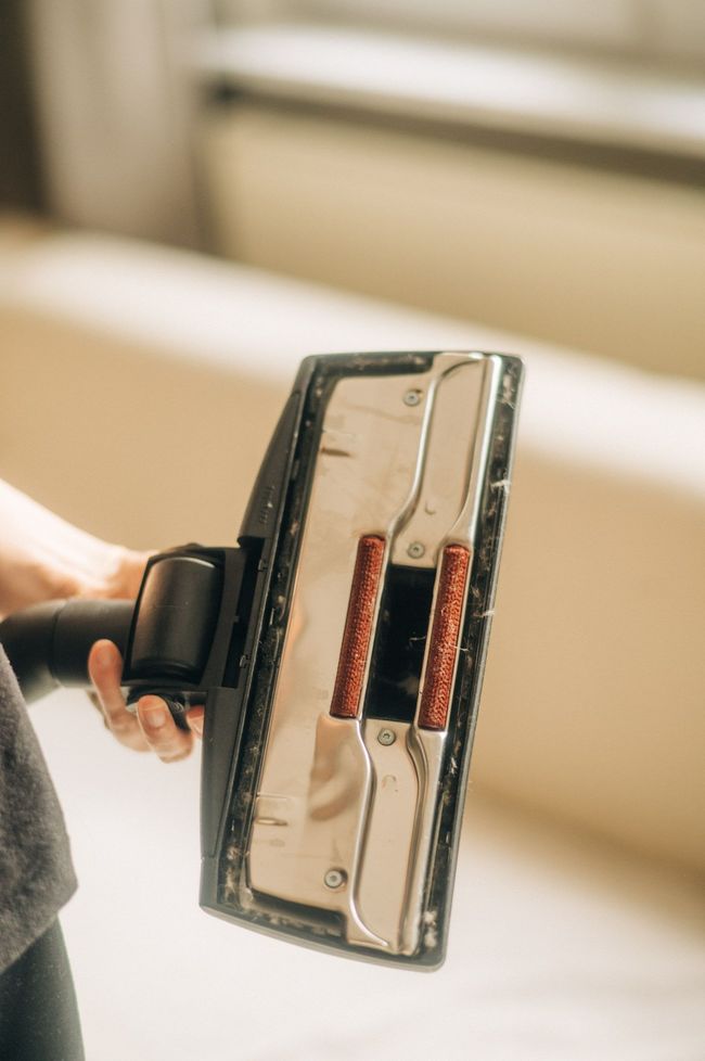 A person is holding a vacuum cleaner brush in their hand.
