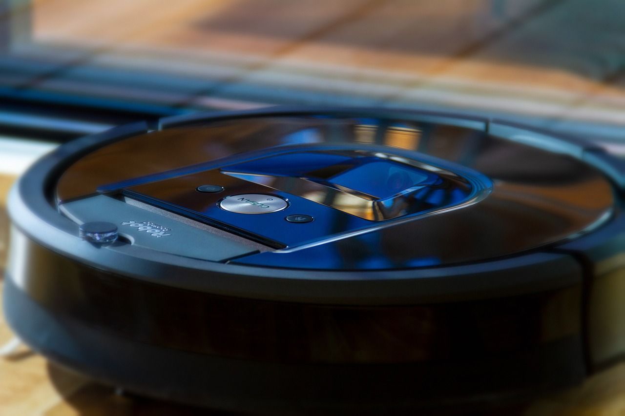 A robot vacuum cleaner is sitting on a wooden table.