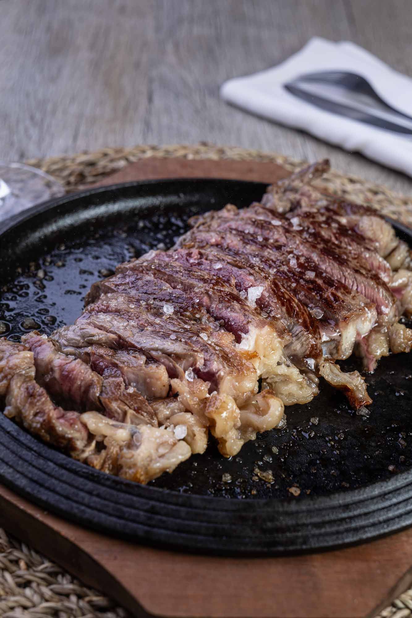 Un filete está sobre una sartén sobre una mesa de madera.