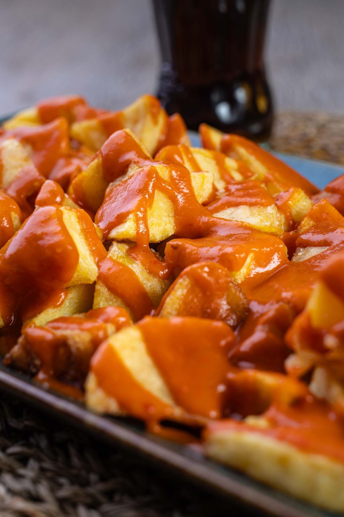Un primer plano de un plato de papas fritas con salsa sobre una mesa.