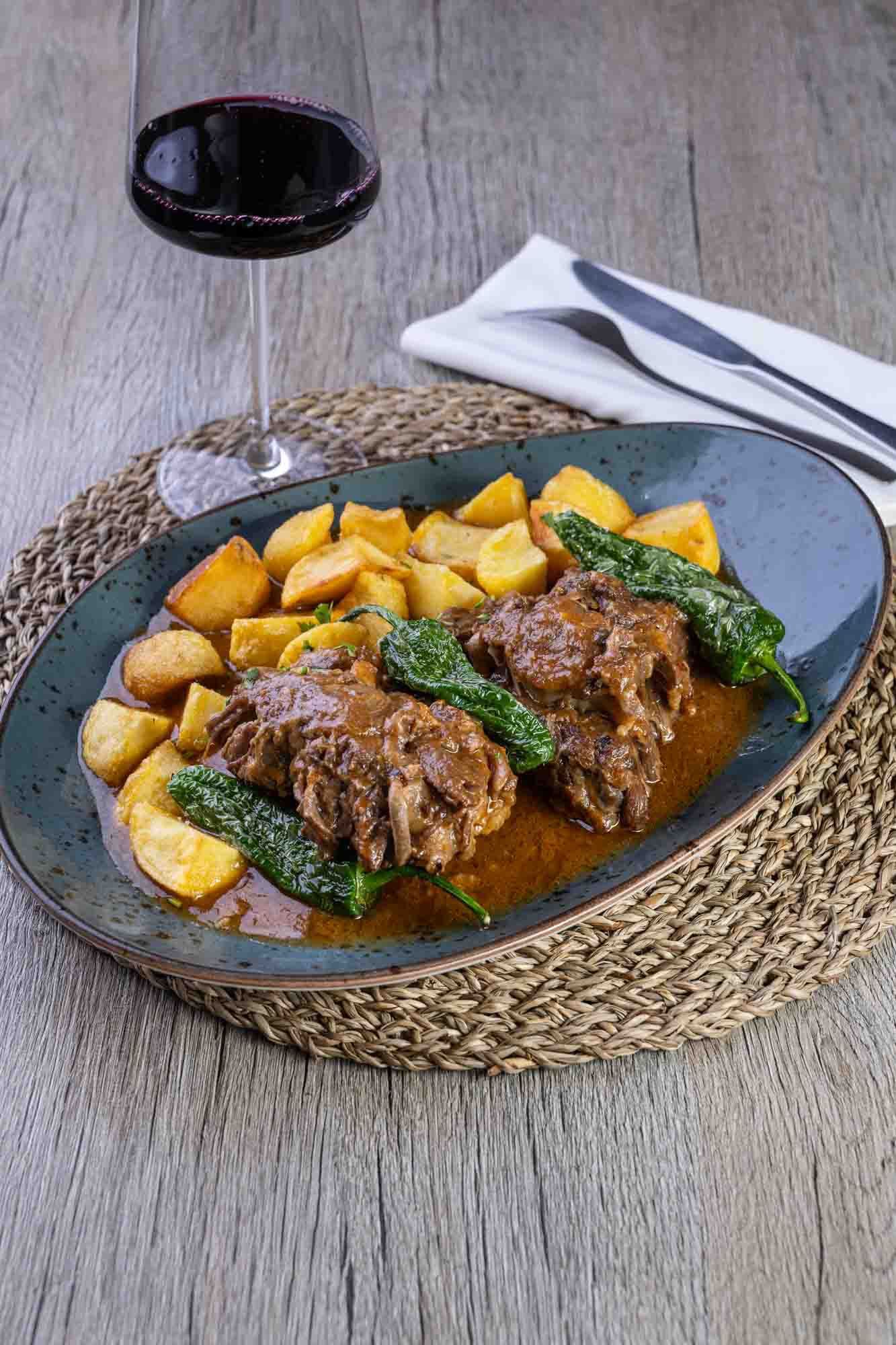 Un plato de comida con una copa de vino en una mesa.
