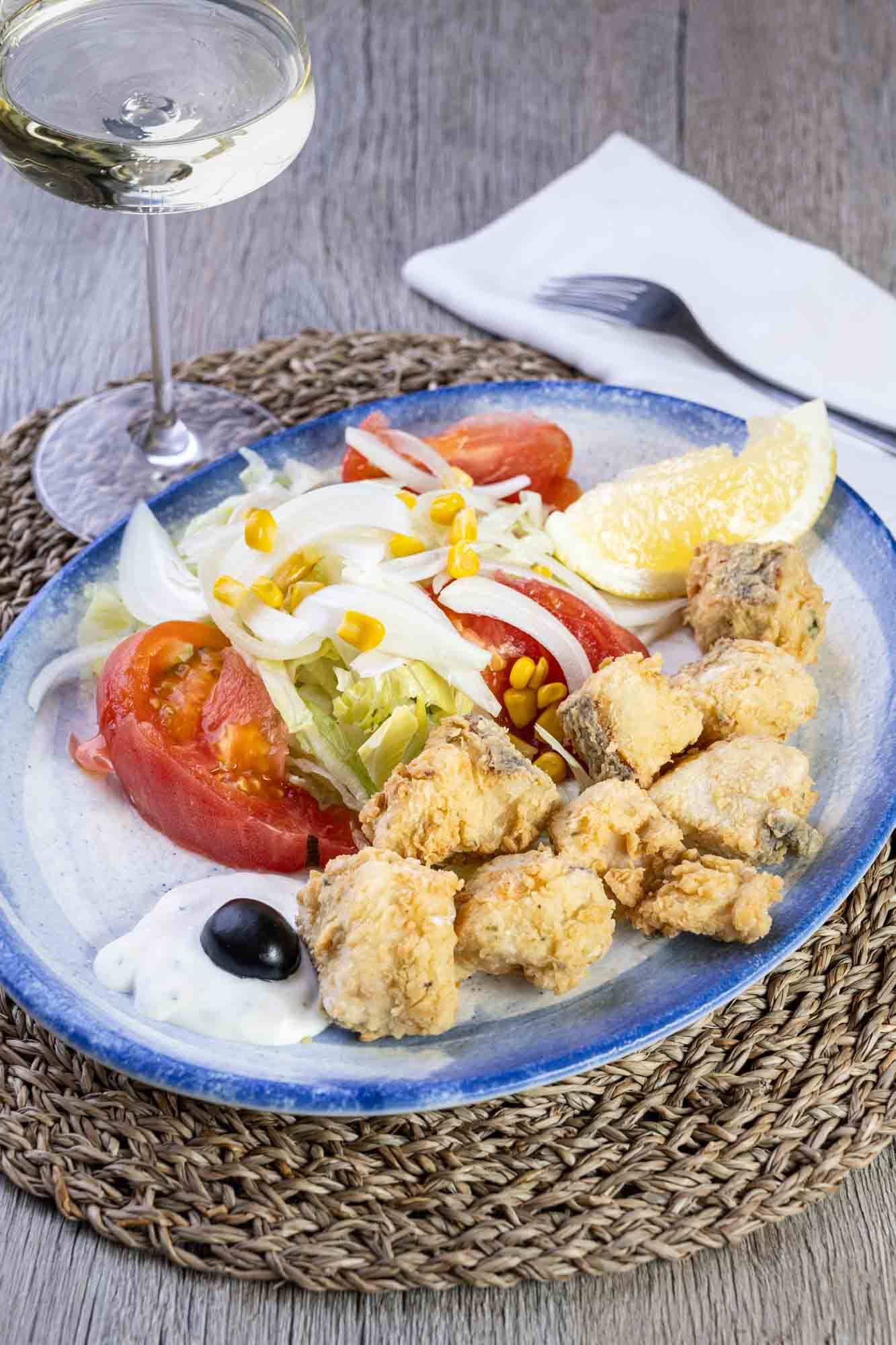 Un plato de comida con una copa de vino en una mesa.