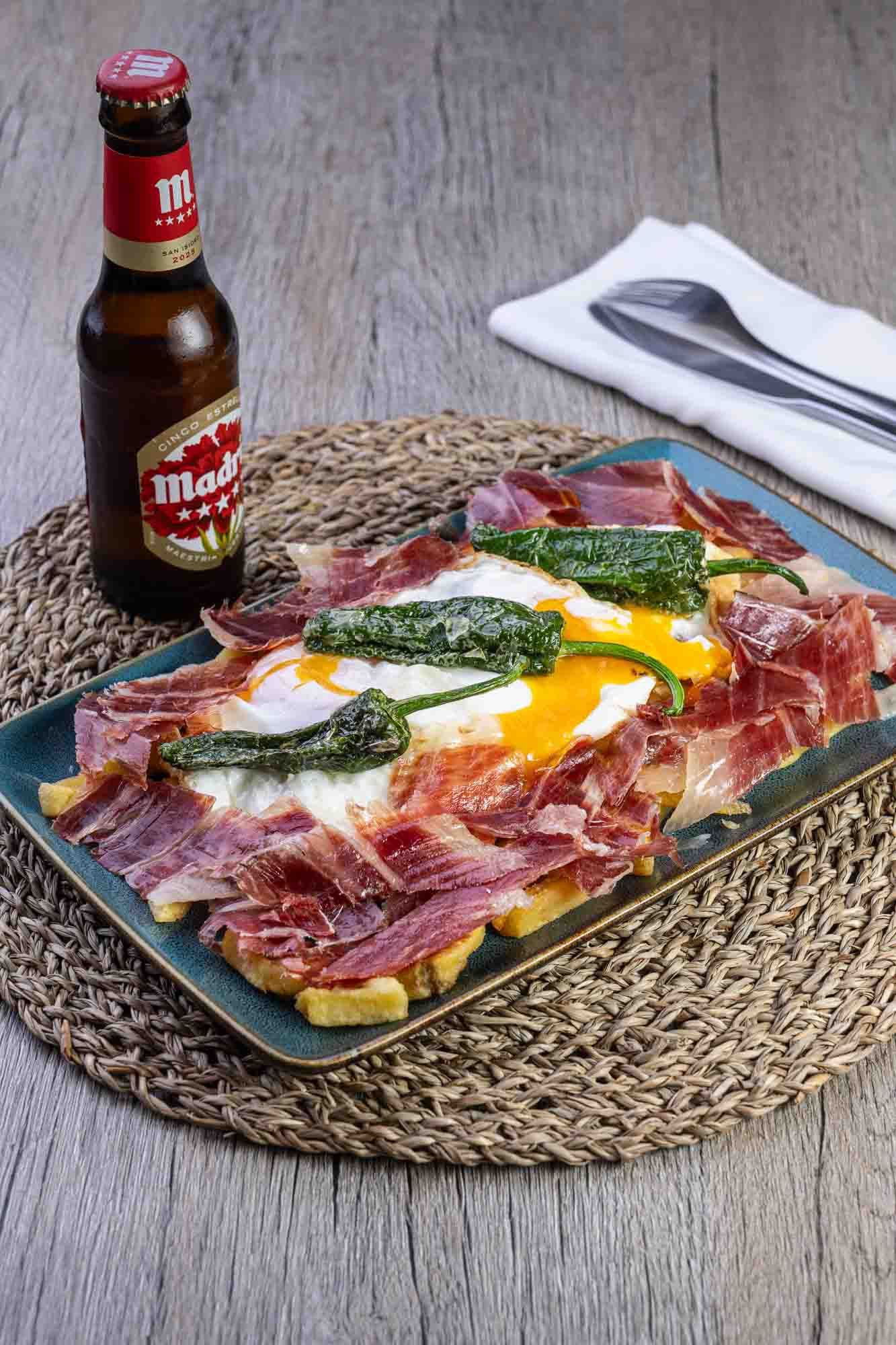 Hay una botella de cerveza al lado de un plato de comida.