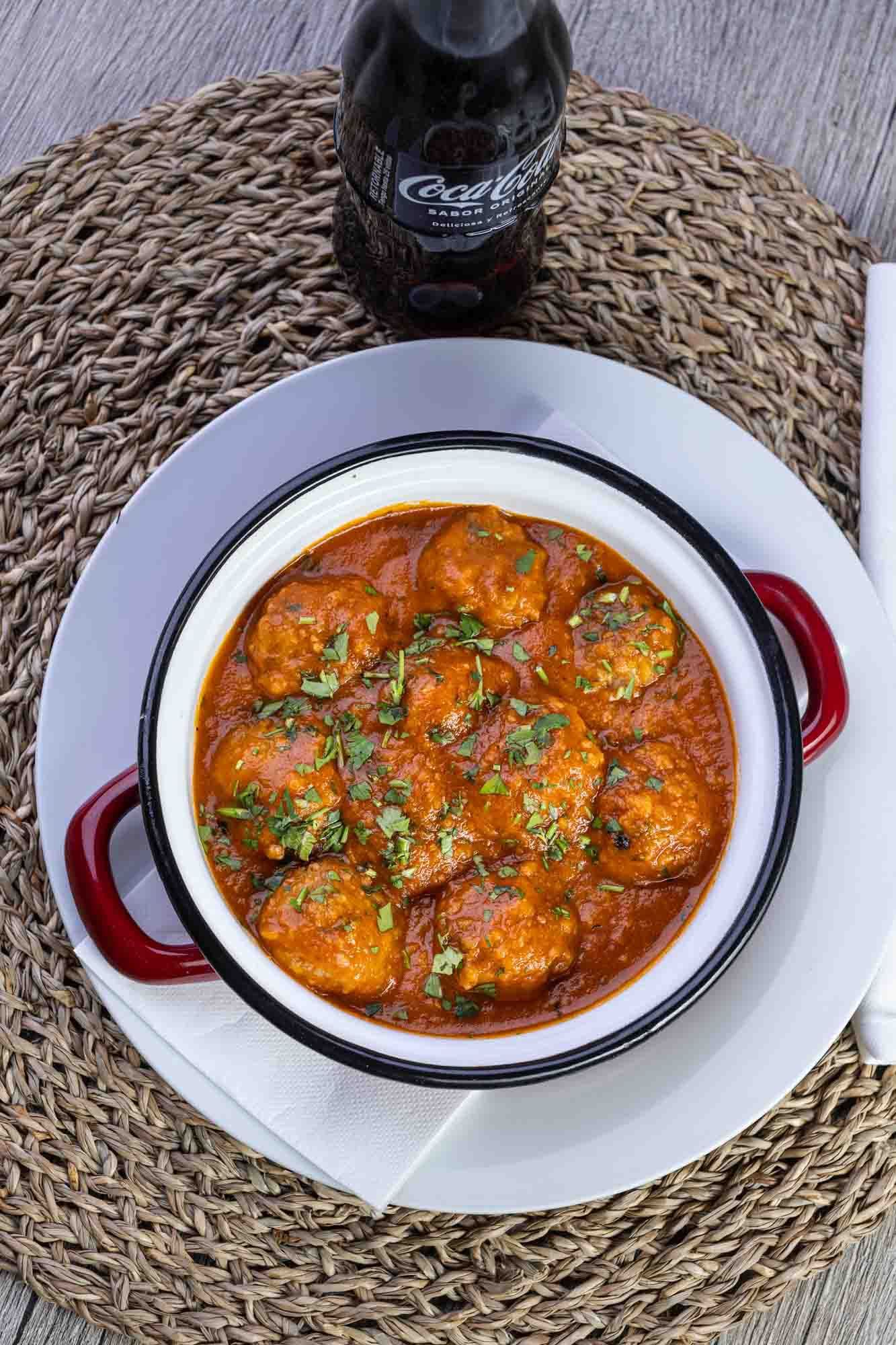 Hay un plato de comida en un plato al lado de una botella de Coca Cola.