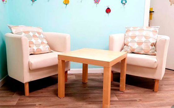 Sala de juegos con suelo de colores, equipamiento, paredes amarillas y una ventana.