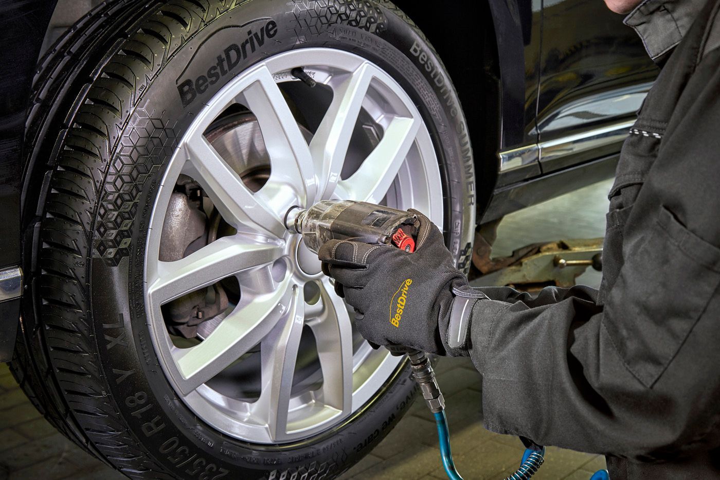 Mecánico que utiliza una llave de impacto para apretar las tuercas de un neumático de automóvil.