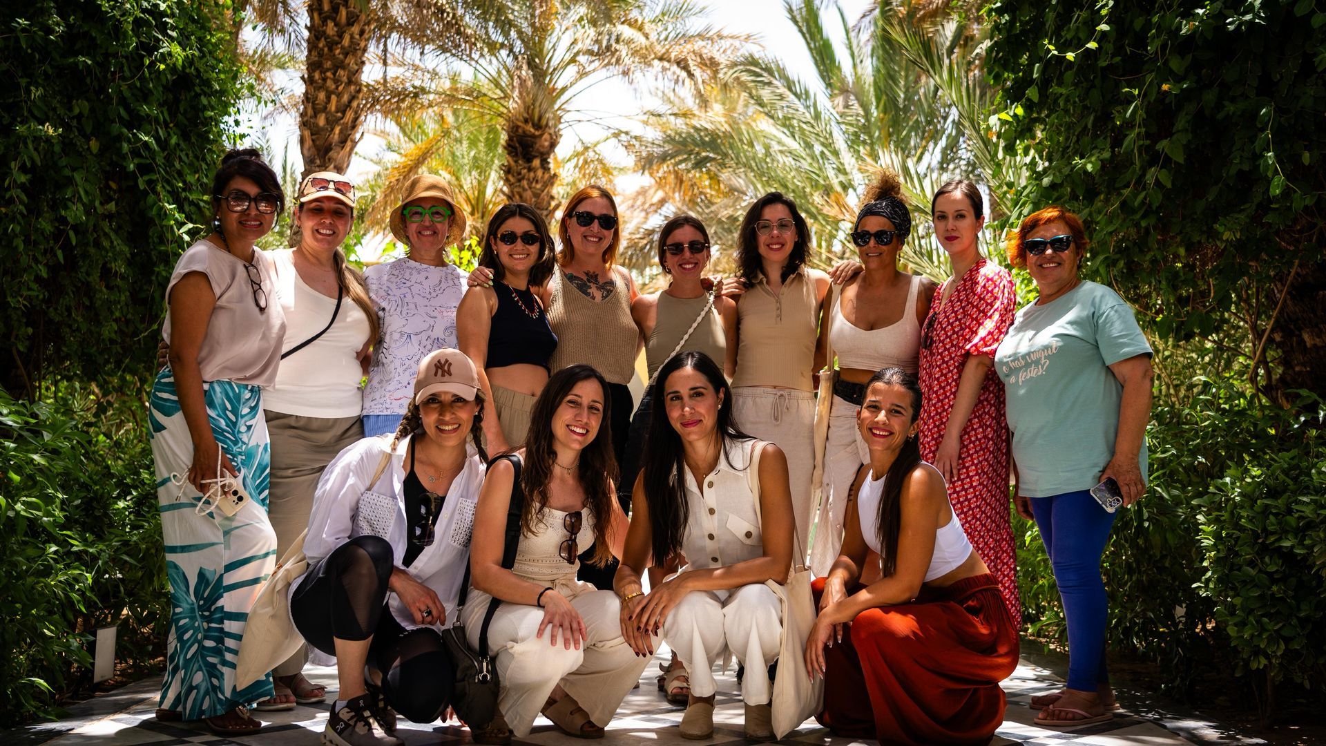 Grupo de personas posando al aire libre con un fondo de montaña, día soleado.
