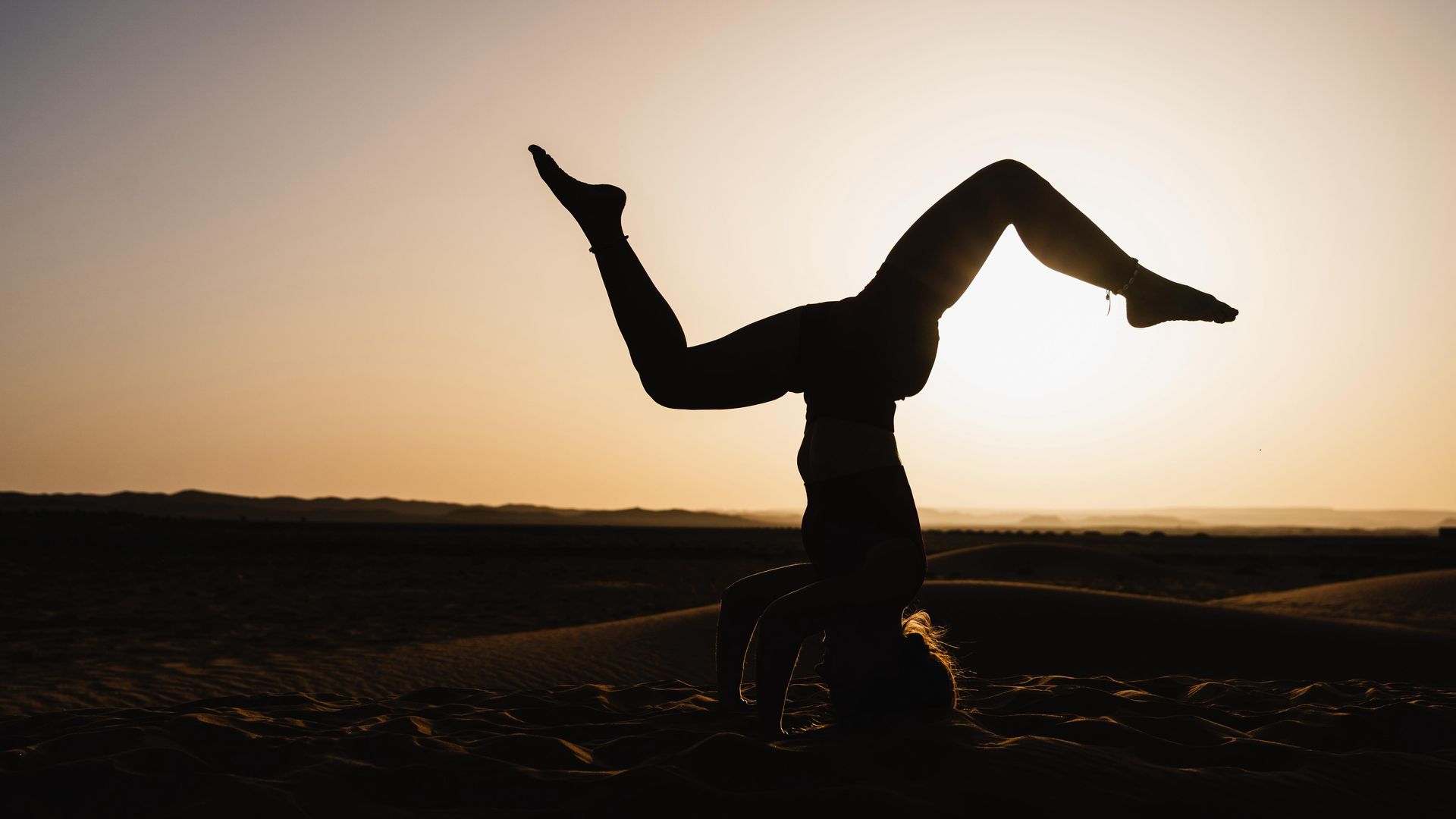 Telas de colores secándose en un tendedero en un pueblo del desierto con montañas al fondo.