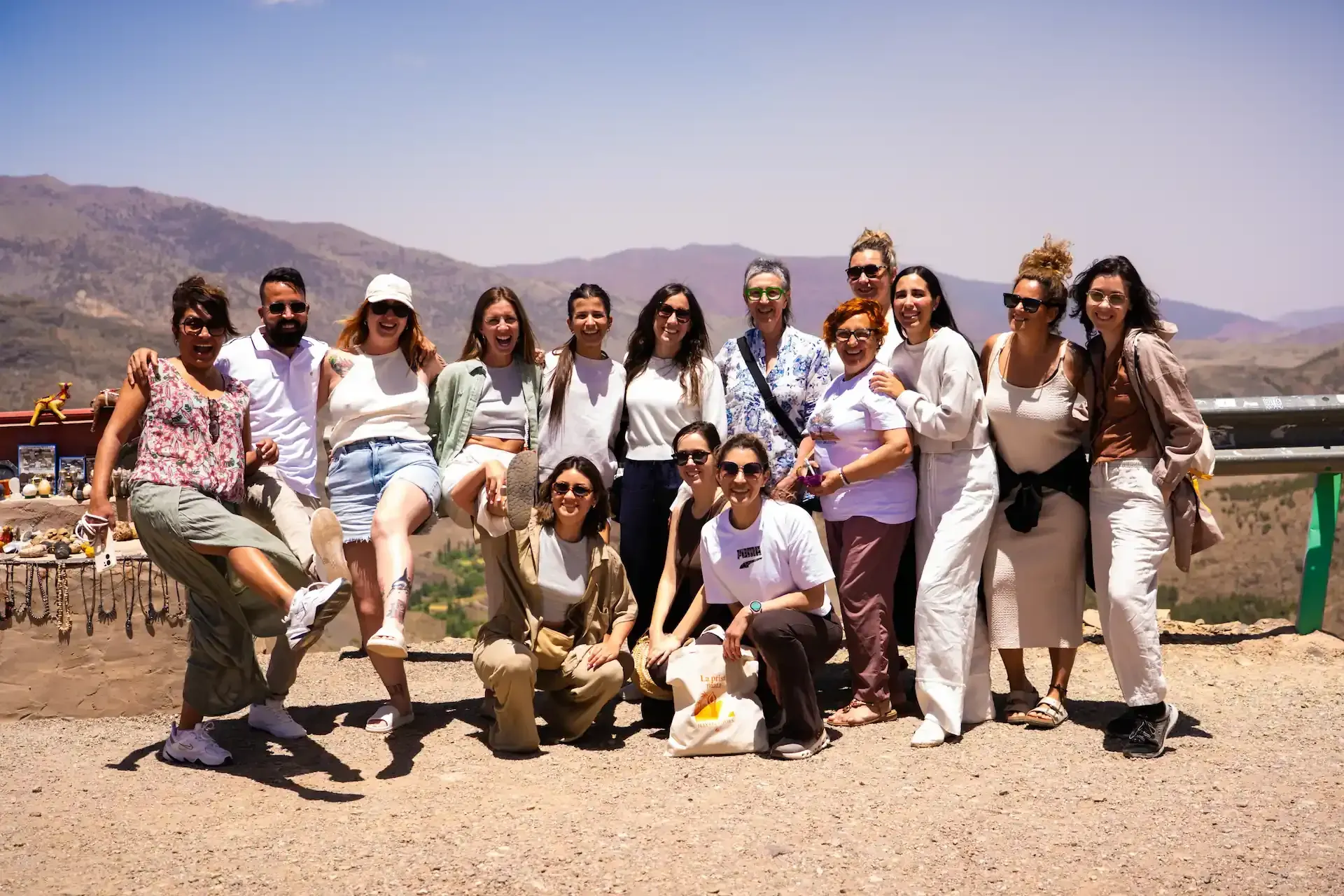 Grupo de personas posando al aire libre con un fondo de montaña, día soleado.