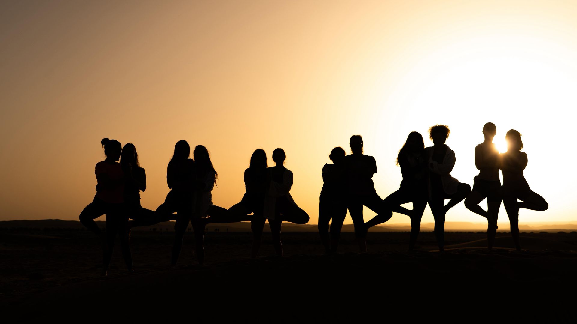 Telas de colores secándose en un tendedero en un pueblo del desierto con montañas al fondo.