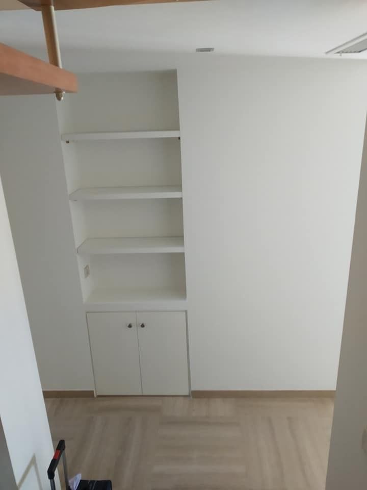 Una habitación con una escalera y estantes en la pared.