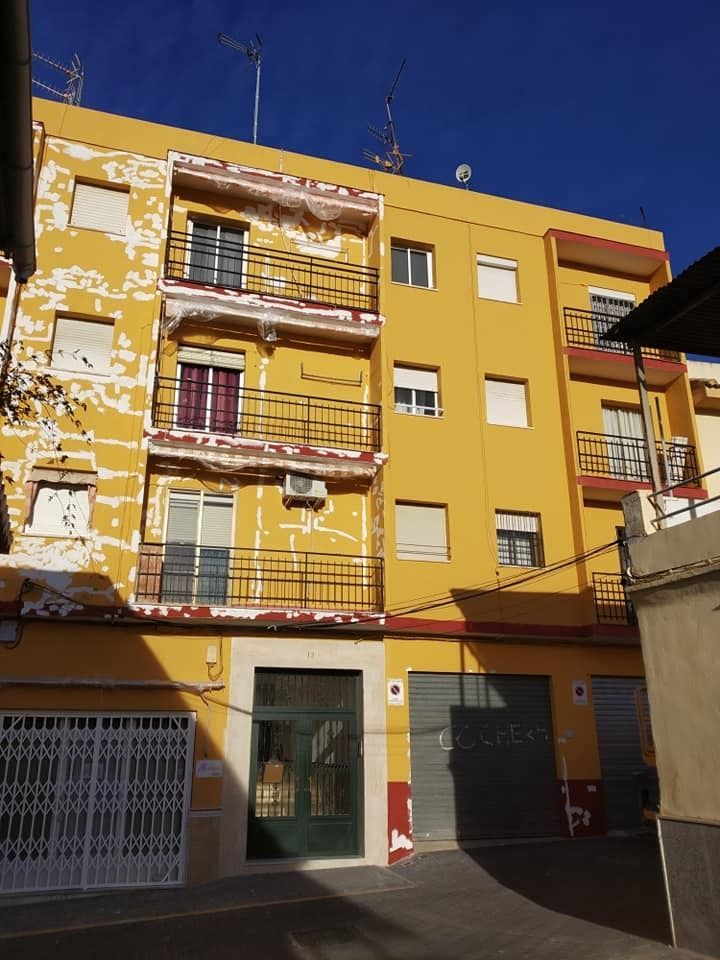 Un edificio amarillo con muchas ventanas y balcones.