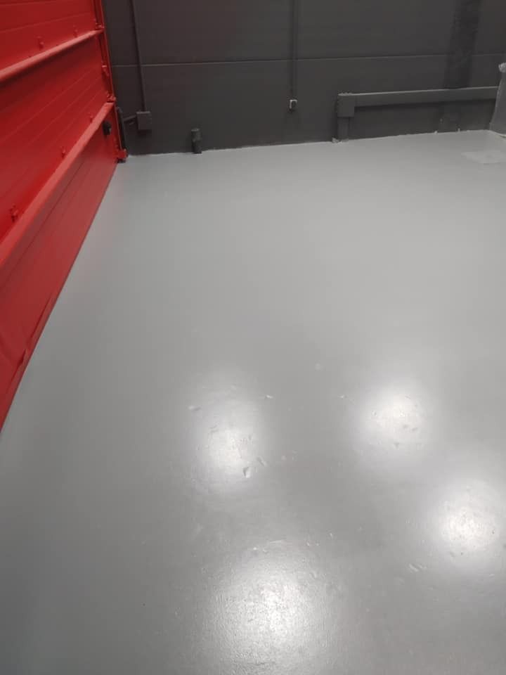 Una habitación con un suelo gris y una pared roja.