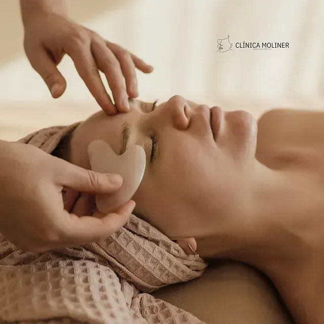 Una mujer acostada en una cama recibiendo un masaje en la Clínica Moliner.
