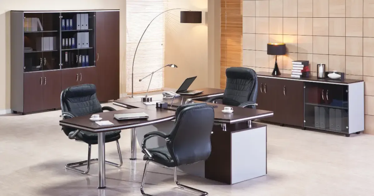 Modern office with desk chairs, shelving, cabinets, and a meeting table in a beige room.
