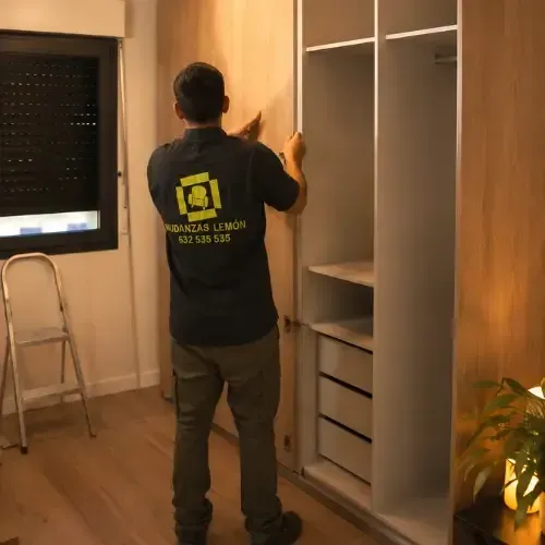 Person assembling a white wardrobe in a bright room, with tools and a window nearby.