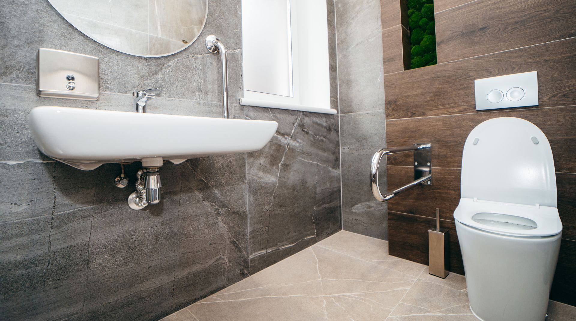 Salle de bains moderne avec lavabo blanc, toilettes et murs carrelés gris foncé.