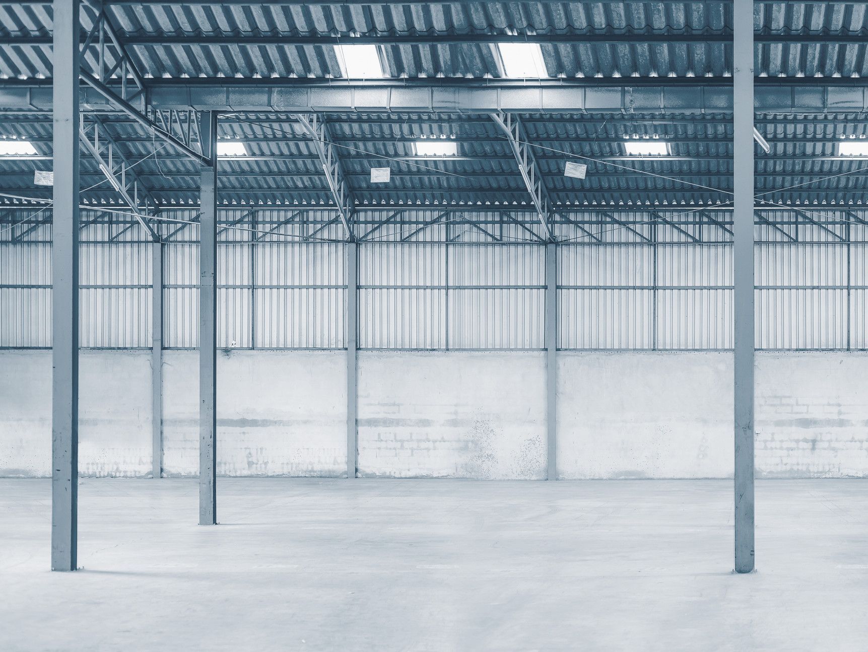 Un almacén vacío con techo de metal y piso de concreto.