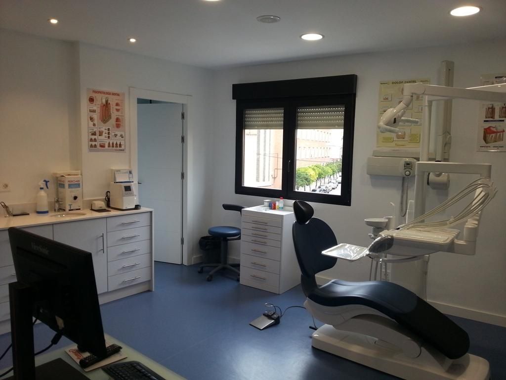 Interior del consultorio dental con sillón dental, ventana, armarios y equipo médico.