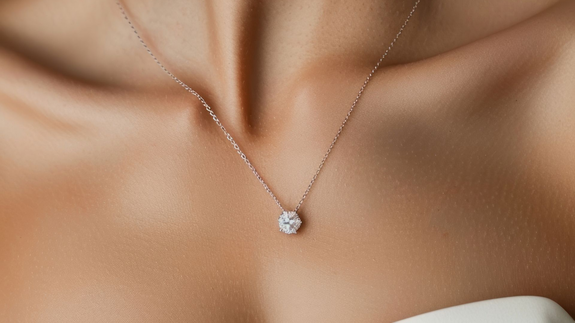 Collier en or rose avec un seul pendentif transparent de taille ovale posé sur la peau d'une personne.