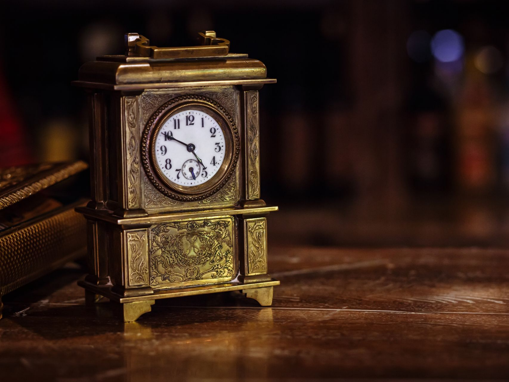 Horloge antique en laiton sur une surface en bois, avec un arrière-plan flou.