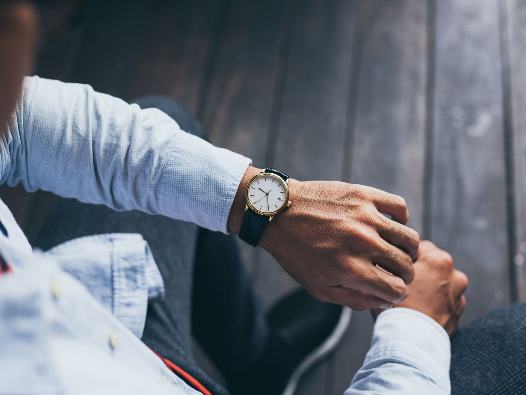 Personne regardant une montre-bracelet avec un bracelet noir et un cadran doré.