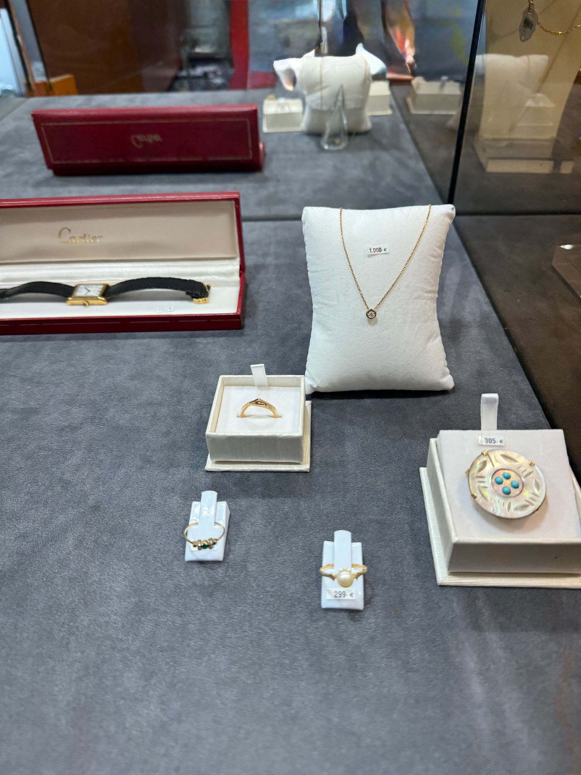 Deux alliances en or, une avec des pierres vertes, une avec des pierres claires, sur une carte avec un motif de feuille verte.