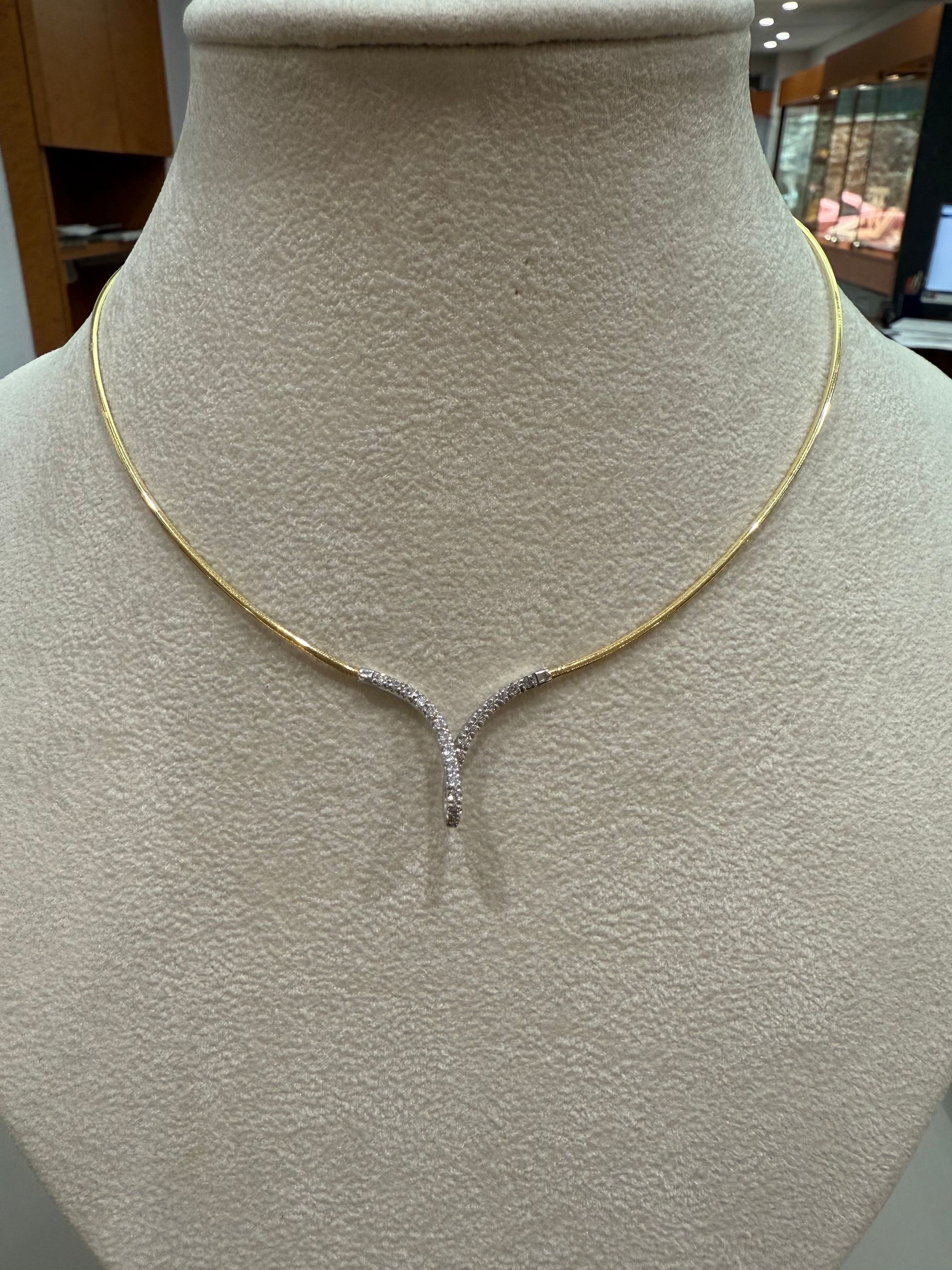 Collier en or rose avec un seul pendentif transparent de taille ovale posé sur la peau d'une personne.