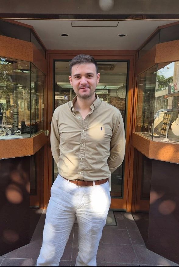 Femme aux cheveux auburn en queue de cheval basse, portant un haut noir et des boucles d'oreilles pendantes, vue de profil.