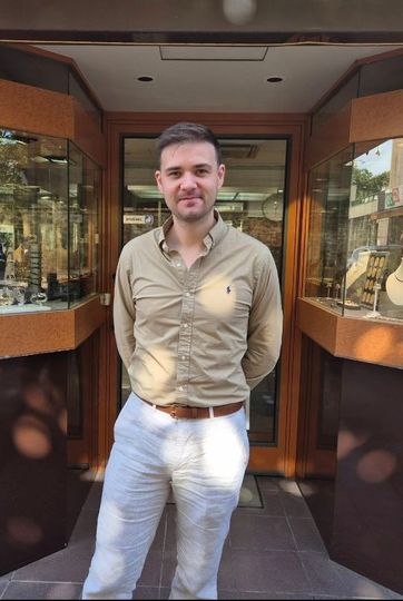 Femme aux cheveux auburn en queue de cheval basse, portant un haut noir et des boucles d'oreilles pendantes, vue de profil.