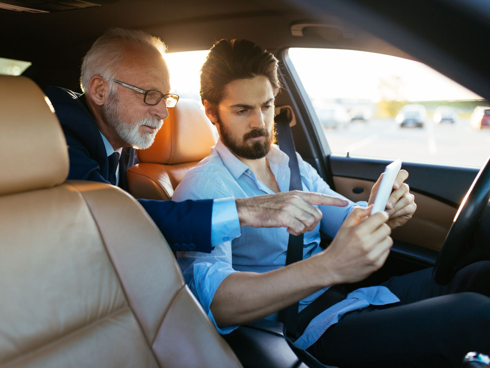 Deux hommes dans une voiture regardant un téléphone.