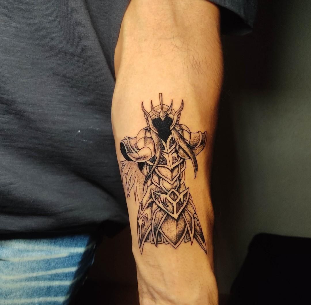 Tatuaje en el brazo de una figura encapuchada con una armadura ornamentada, con un rostro oscuro y sin rasgos distintivos, de pie con los brazos extendidos.