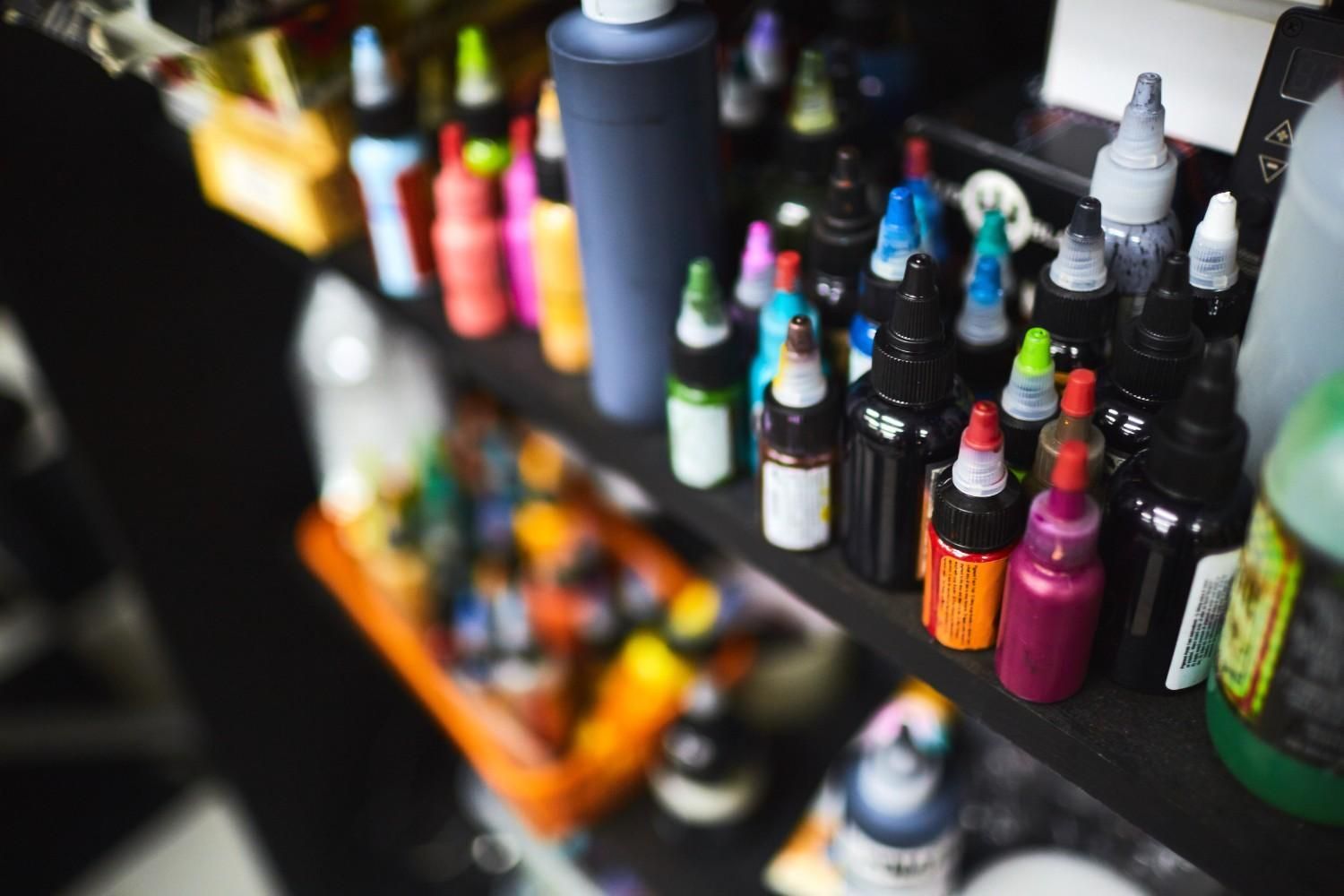 Botellas de tinta de tatuaje de colores en un estante en un estudio de tatuajes.