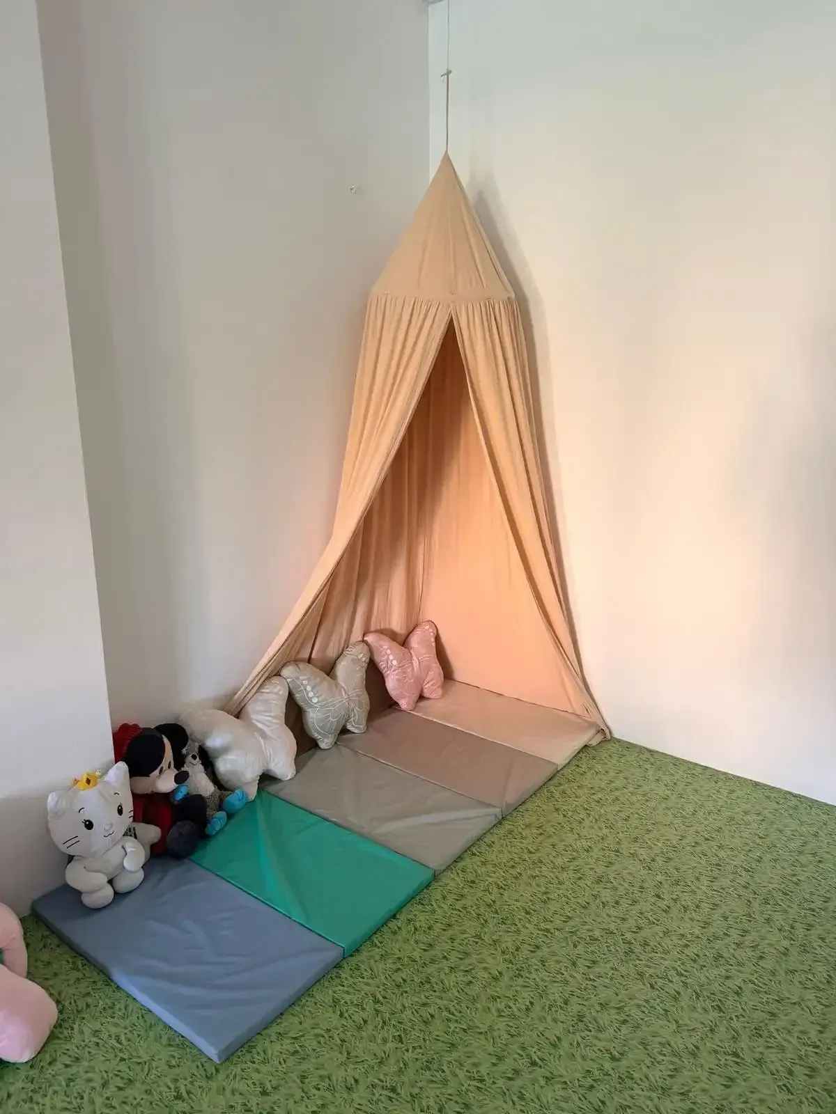 Rincón de juegos para niños con una tienda de campaña beige con dosel
