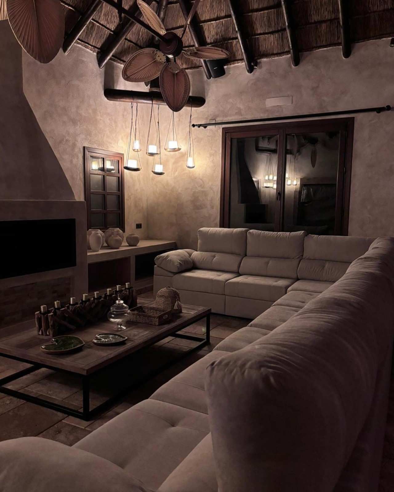 Acogedora sala de estar con un sofá seccional color crema, una mesa de café de madera y una iluminación cálida.