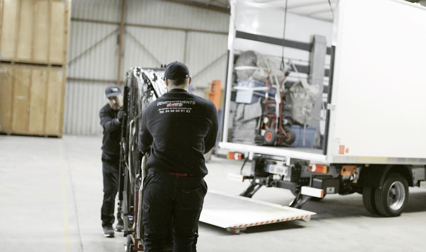 Deux déménageurs qui s'apprêtent a charger un piano dans un camion